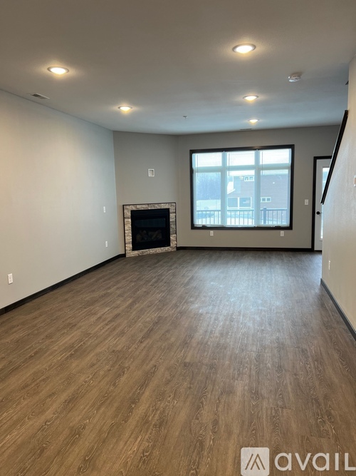 A spacious room with wooden flooring and a large window.