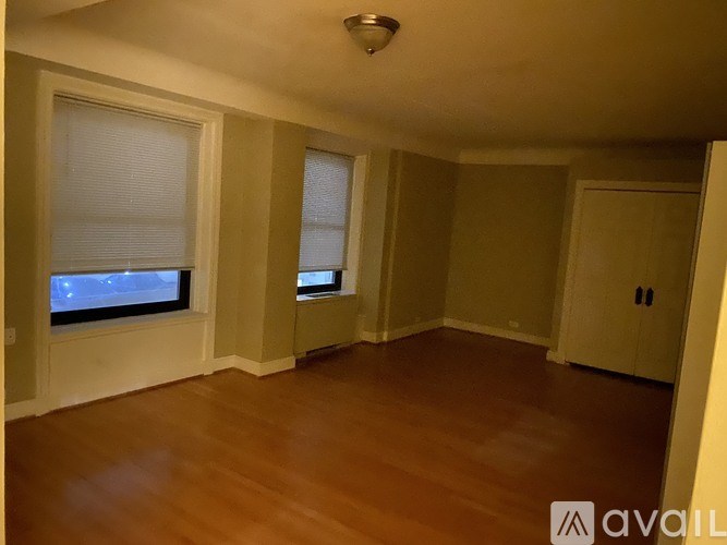 A room with wooden floors and a window showing a view of a street.