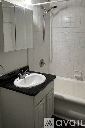 A bathroom with a sink, mirror, and bathtub.