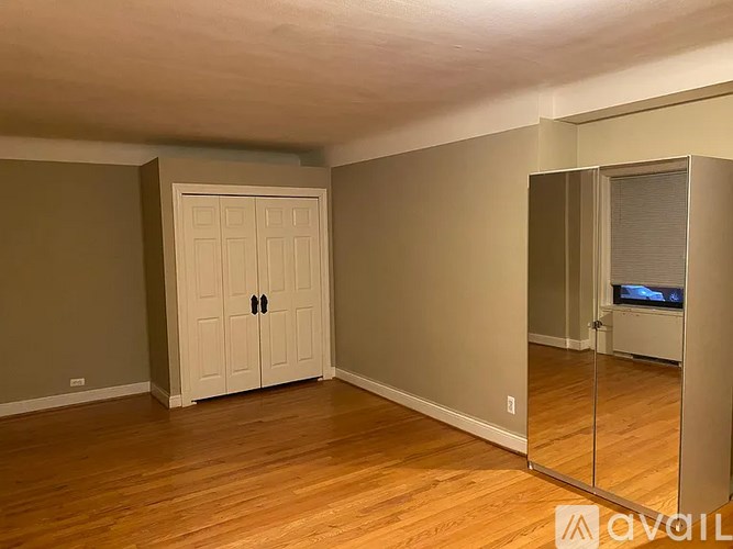 A room with a white door and wooden flooring.