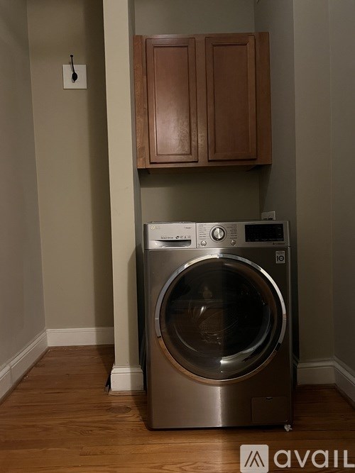 A washing machine in a laundry room with wooden cabinets.