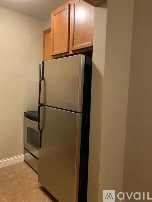 A stainless steel refrigerator with wooden cabinets on top.