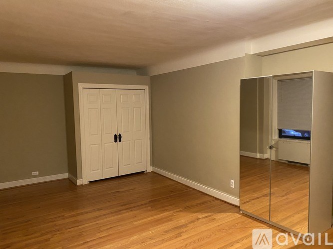 A room with a white door and wooden flooring.