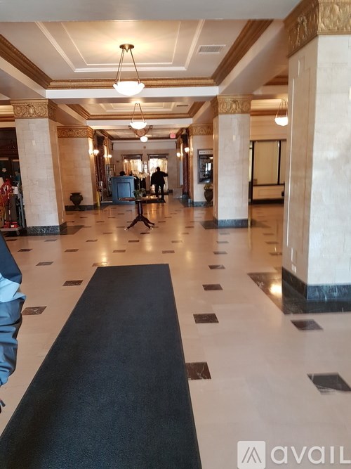A hallway with a black carpet and white marble flooring.