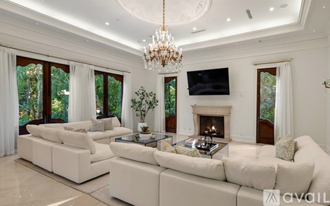 A living room with a white sofa set, a chandelier, and a fireplace.