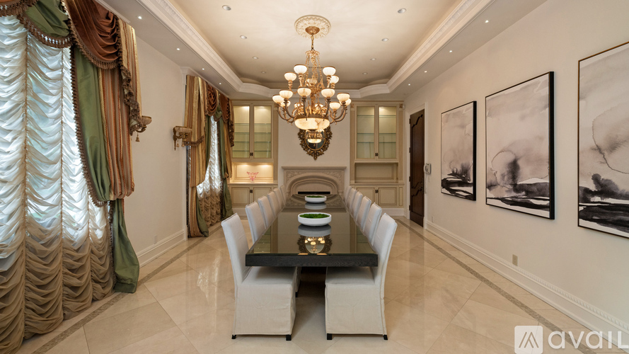 A dining room with a long table and chairs, a chandelier, and pictures on the wall.