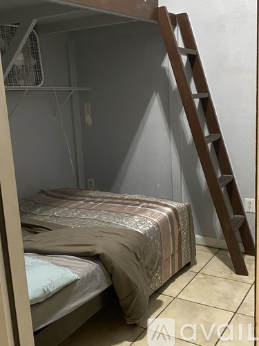 A bedroom with a bed and a ladder.