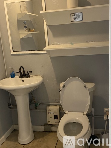 A white toilet is in a bathroom with a sink and mirror.