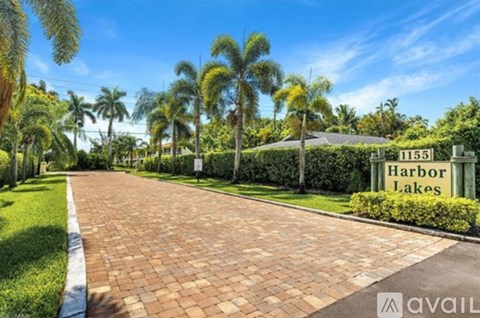A sign for Harbor Lakes is visible in front of a pathway lined with palm trees.