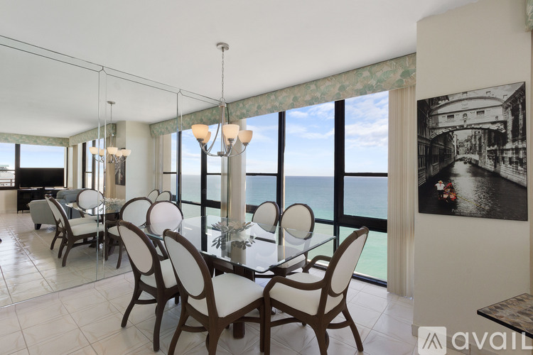 A dining room with a table set for six with a view of the ocean.