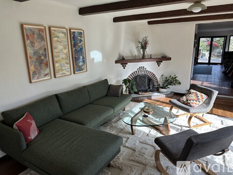 A living room with a green couch and a glass coffee table.