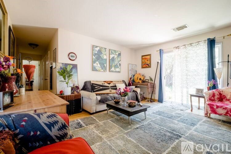 A living room with a couch, a coffee table, and a guitar on the wall.