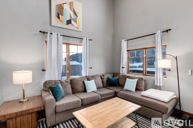A living room with a grey couch, a wooden table, and a painting on the wall.