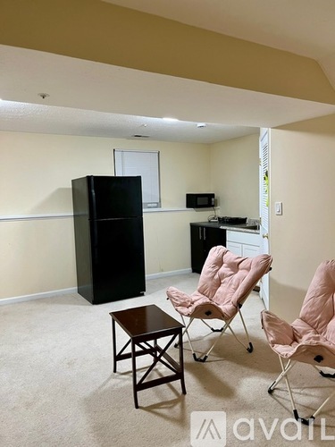A living room with a black refrigerator, a small table, and two chairs.