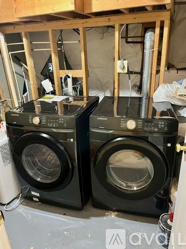 Two front load washing machines in a room under construction.