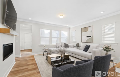 A living room with a grey sofa, a coffee table, and a television on the wall.