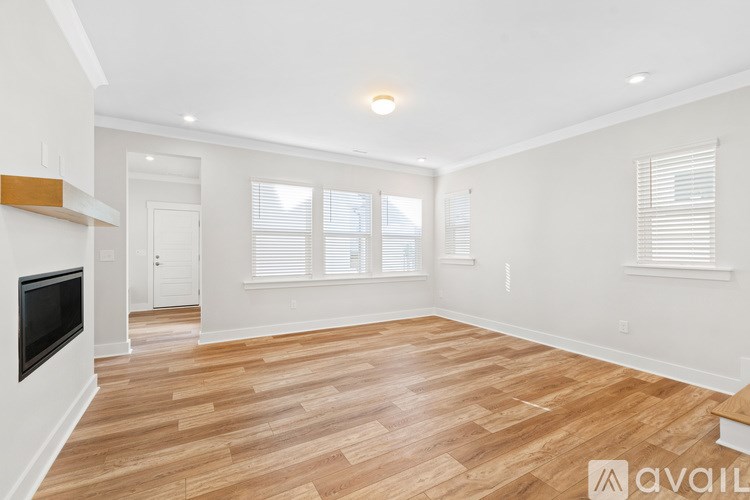 A spacious living room with wooden flooring and a television.