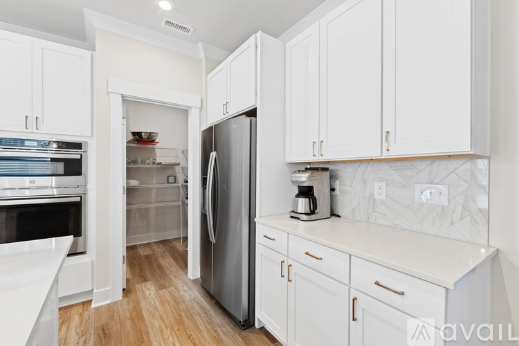 A kitchen with white cabinets and a refrigerator.