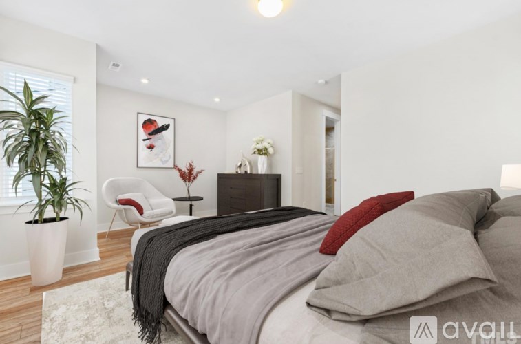 A bedroom with a bed, chair, and potted plant.