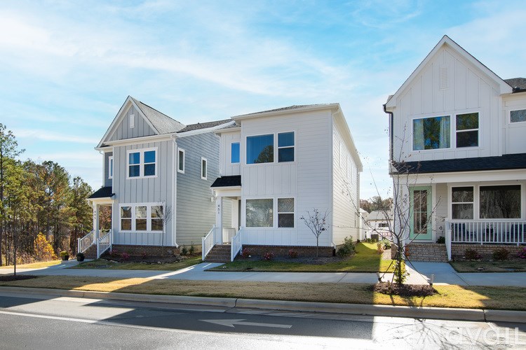 Two houses with white and grey exteriors are situated on a street.