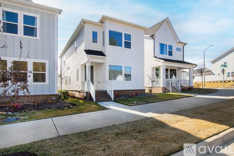 A white house with a brown roof and a driveway in front.
