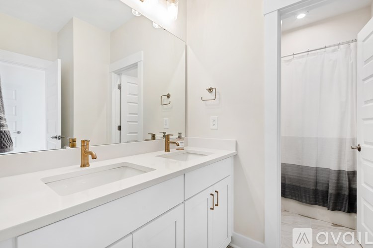 A bathroom with a white sink and gold faucets.