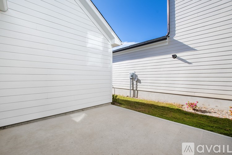 A house with a white siding and a grey roof with a small garden in front.
