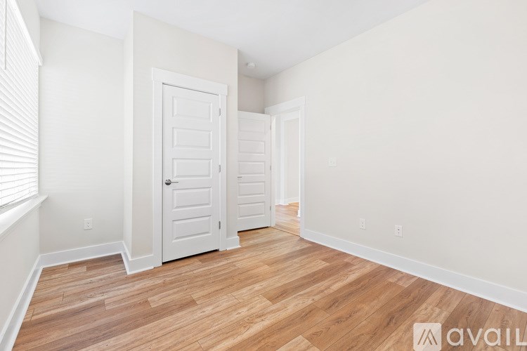 A room with a white door and a wooden floor.