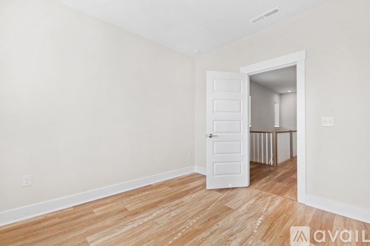 A room with a white door and wooden flooring.
