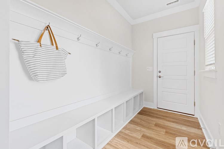 A white room with a striped bag hanging on a hook.