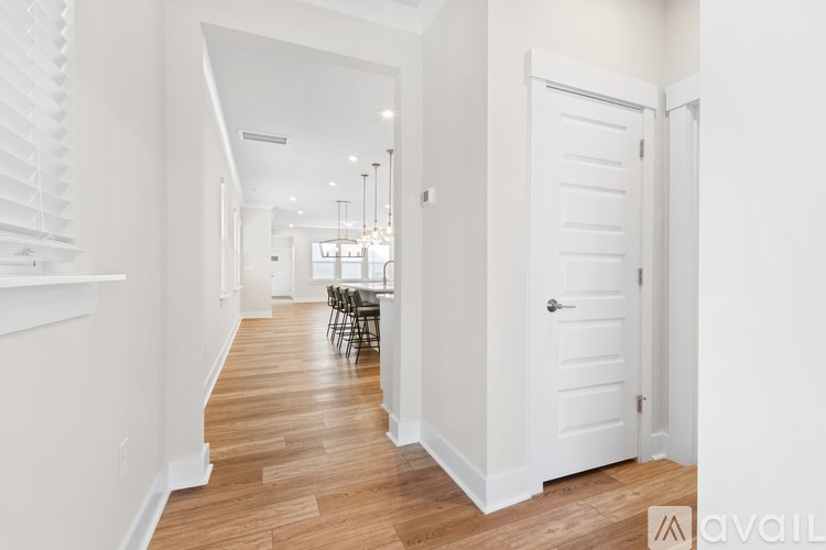 A hallway with a wooden floor and white walls leading to a dining area.