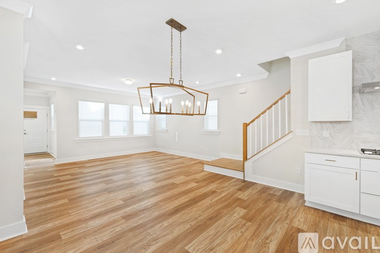 A large open room with wooden floors and a chandelier hanging from the ceiling.