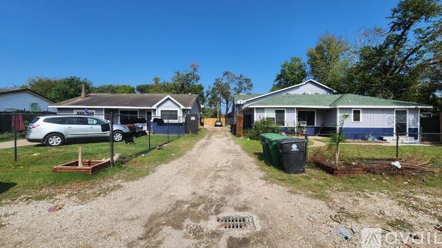 A dirt road leads to a house with a sign that says "For Sale".