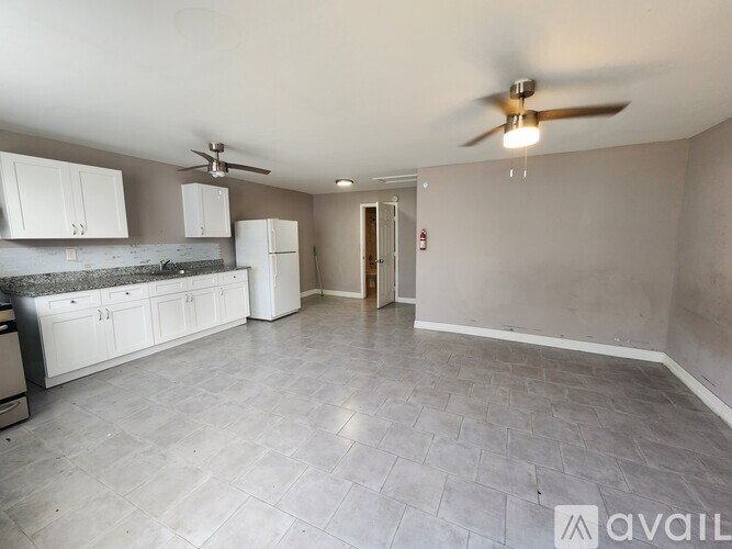 A kitchen with white cabinets and a fan on the ceiling.