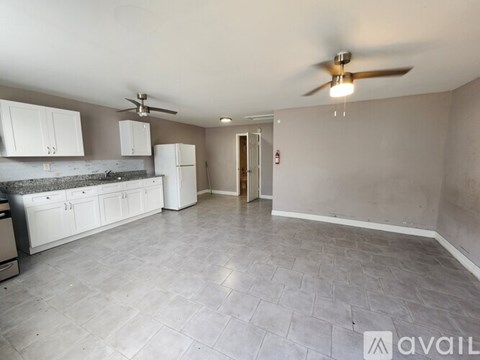 A kitchen with white cabinets and a fan on the ceiling.