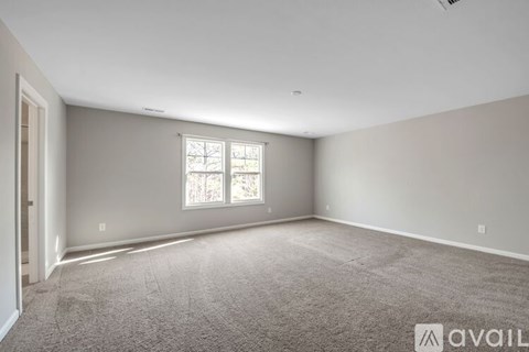 A spacious room with a carpeted floor and a window.
