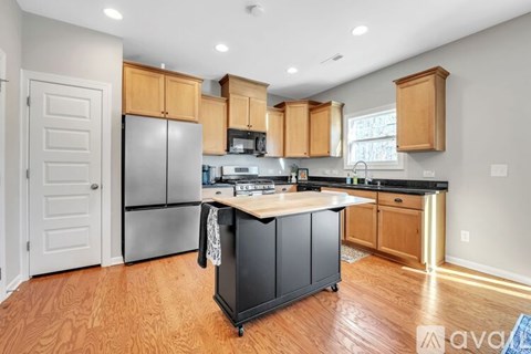 A kitchen with wooden cabinets and a black island.