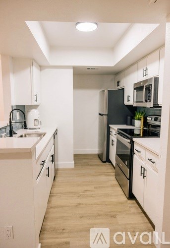 A kitchen with white cabinets and a black fridge.