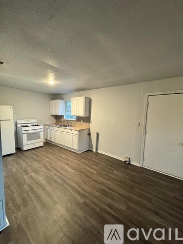 A kitchen with white appliances and wooden floors.