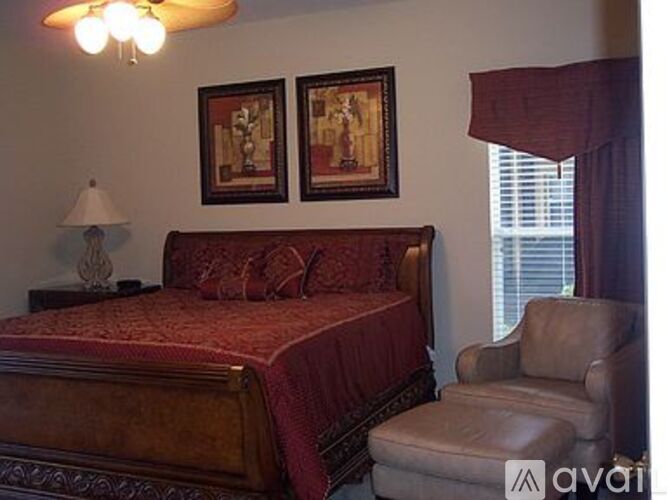 A bedroom with a bed, chair, and two pictures on the wall.