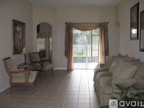 A living room with a couch, chairs, and a painting on the wall.