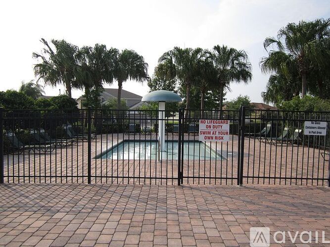 A pool surrounded by a black fence with a warning sign on it.