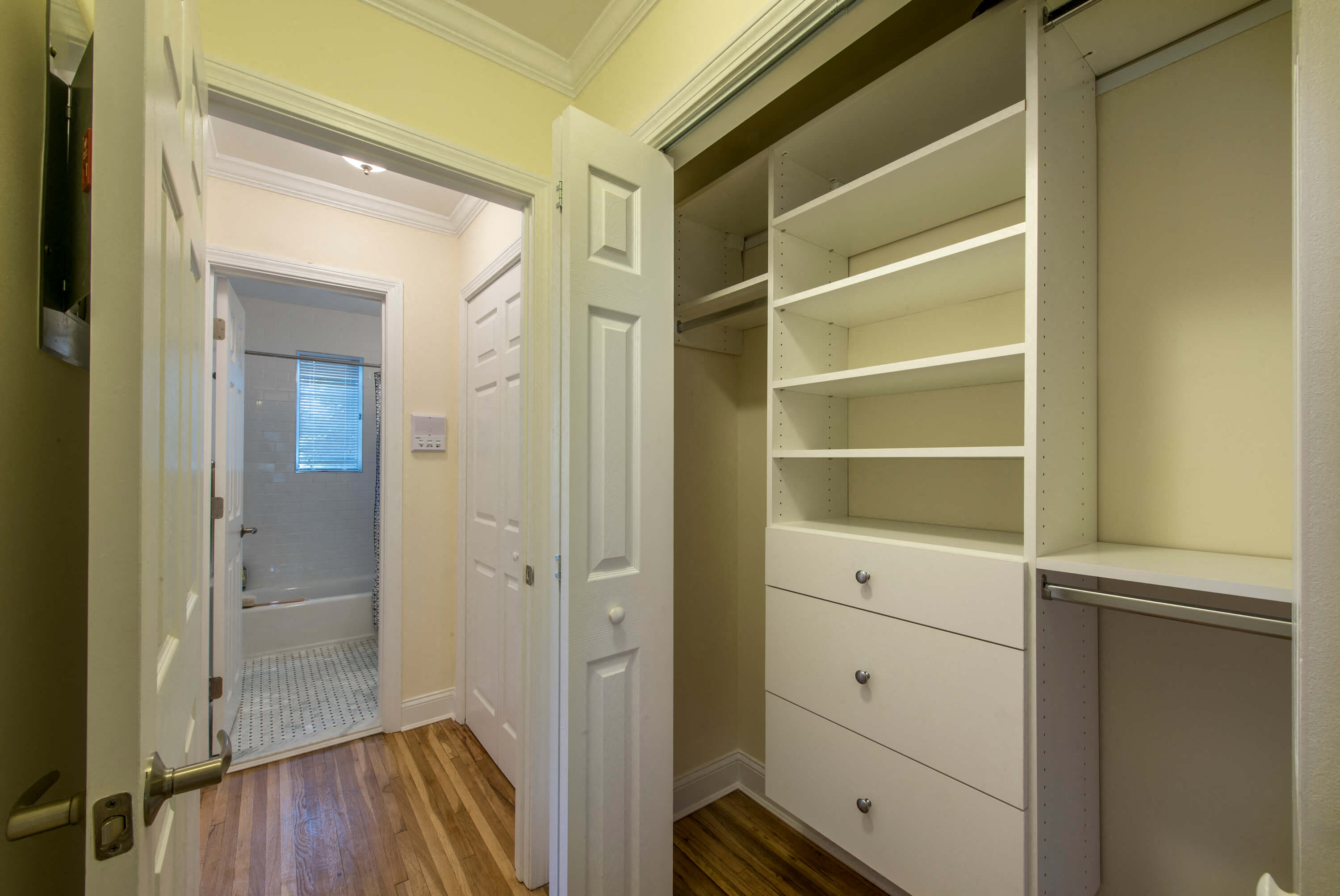 a walk in closet with shelves and a door to the bathroom