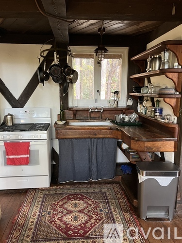 A kitchen with a rug on the floor and a stove top oven.