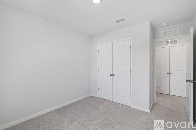 A bedroom with white walls and carpeted floor.