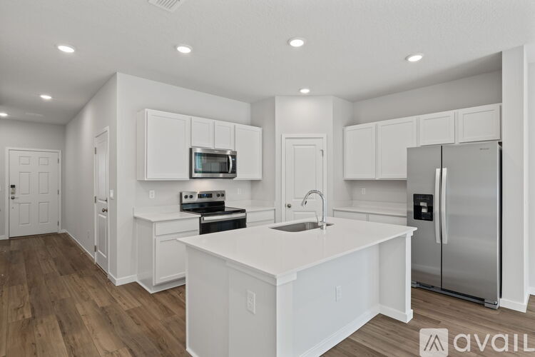 A kitchen with white cabinets and a wooden floor.