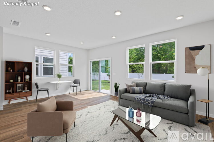 A living room with a grey couch, a brown armchair, a glass coffee table, and a wooden bookshelf.