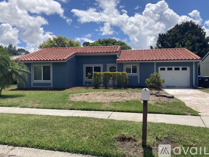 A blue house with a red tile roof and a white garage door.