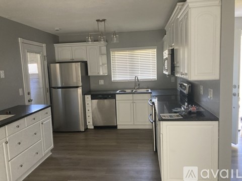 A kitchen with white cabinets and a stainless steel refrigerator.