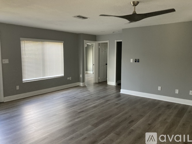 A spacious room with a ceiling fan and wooden flooring.